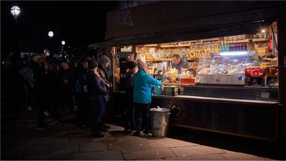 Gente comprando en un comercio callejero.