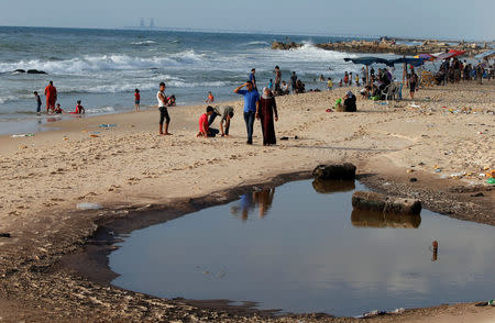 Palestinians walk past a pool of sewage on a beach in the northern Gaza Strip July 13, 2018. REUTERS/Mohammed Salem