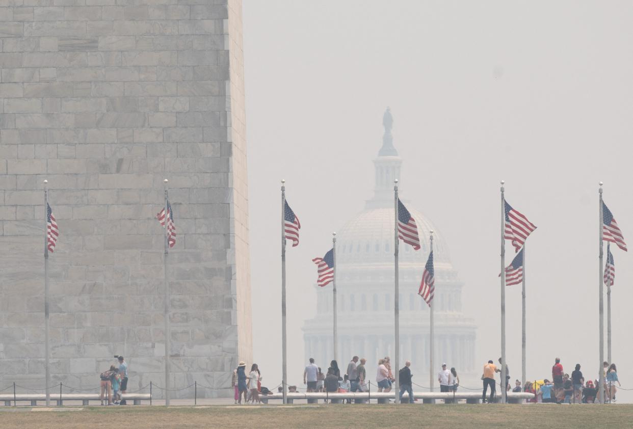Tourists walk on the National Mall as smoke from wildfires in Canada cause hazy conditions in Washington, DC, on June 7, 2023. Residents of the nation's capital woke Wednesday to an acrid smell and cloudy skies despite sunny weather. Washington authorities warned that the air quality was "unhealthy for people with heart or lung disease, older adults, children and teens" and canceled all outdoor activities in public schools, including sports lessons.