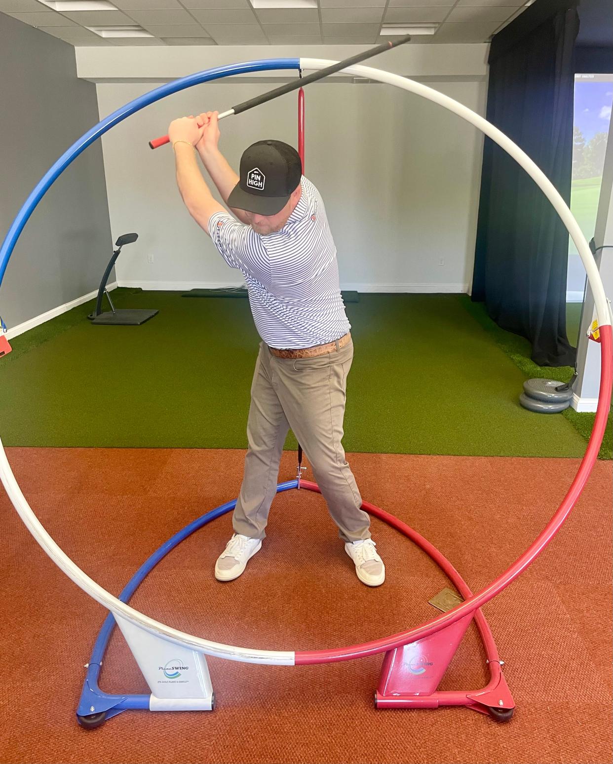 Dan Boisvert swings a club inside a golf swing trainer.