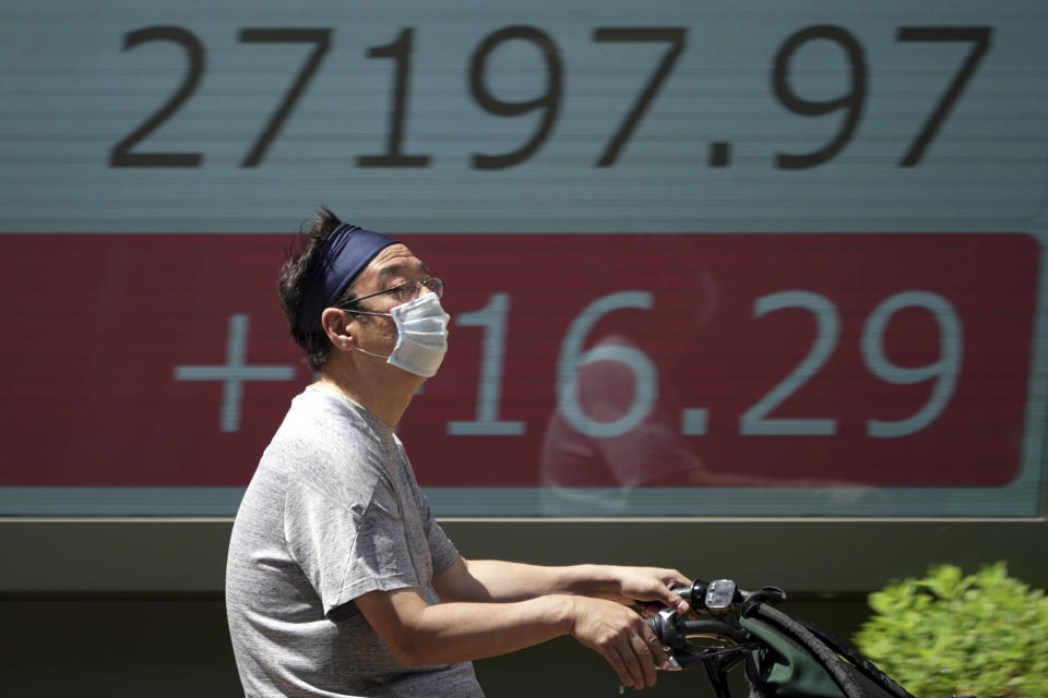 A man wearing a protective mask rides a bicycle in front of an electronic stock board showing Japan's Nikkei 225 index at a securities firm Monday, May 30, 2022, in Tokyo. Asian stocks rose Monday after Wall Street rebounded from a seven-week string of declines and China eased anti-virus curbs on business activity in Shanghai and Beijing. (AP Photo/Eugene Hoshiko)