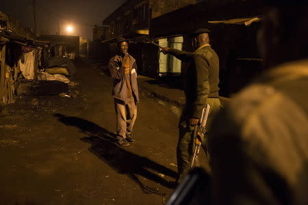 A police officer gestures to a man on a street in Korogocho during a night patrol in Nairobi, Kenya, October 30, 2015. REUTERS/Siegfried Modola