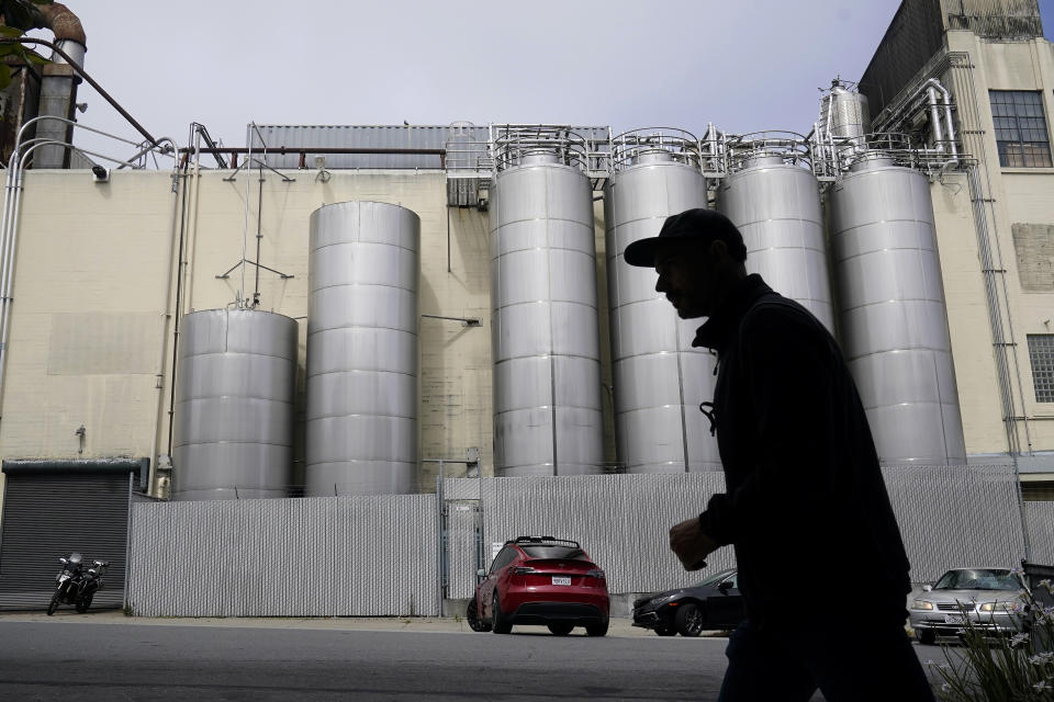 FILE - A person walks across the street from Anchor Brewing Co. in San Francisco, Wednesday, July 12, 2023. A spokesman for Anchor Brewing says the company is open to a purchase offer from its employees but warned that time is running out. The 127-year-old San Francisco-based trailblazer of craft beers stunned beer lovers earlier in July when it announced it would cease operations. (AP Photo/Jeff Chiu,File)