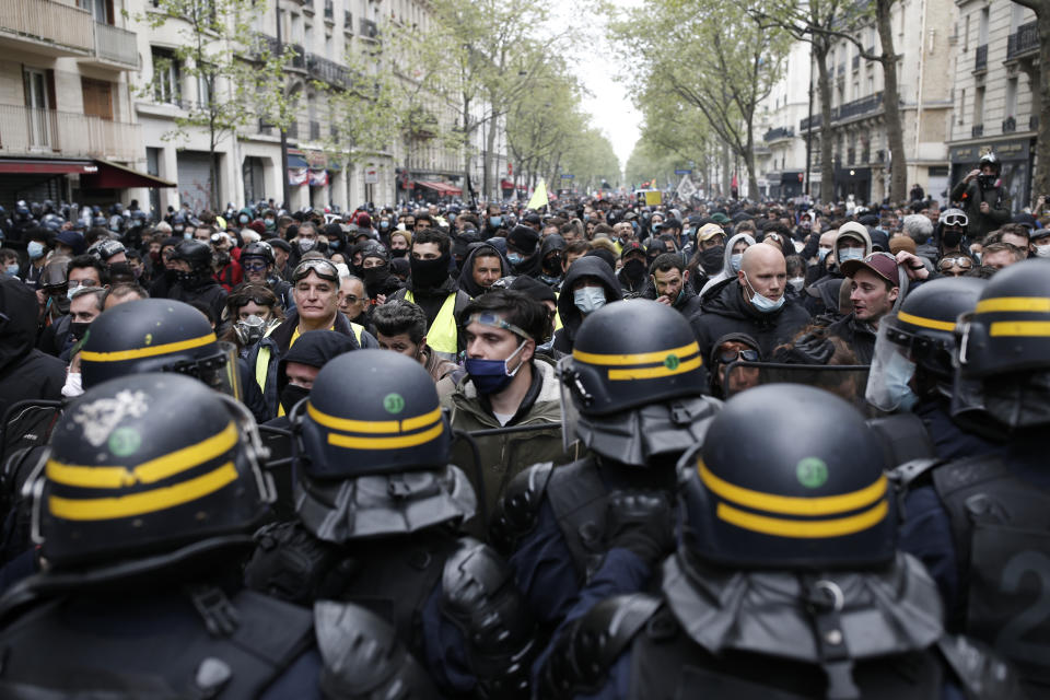 Riot police officers frame demonstrators during May Day march, Saturday, May 1, 2021 in Paris. Workers and union leaders dusted off bullhorns and flags that had stayed furled during coronavirus lockdowns for slimmed down but still boisterous May Day marches on Saturday, demanding more labor protections amid a pandemic that has turned economies and workplaces upside down. (AP Photo/Lewis Joly)