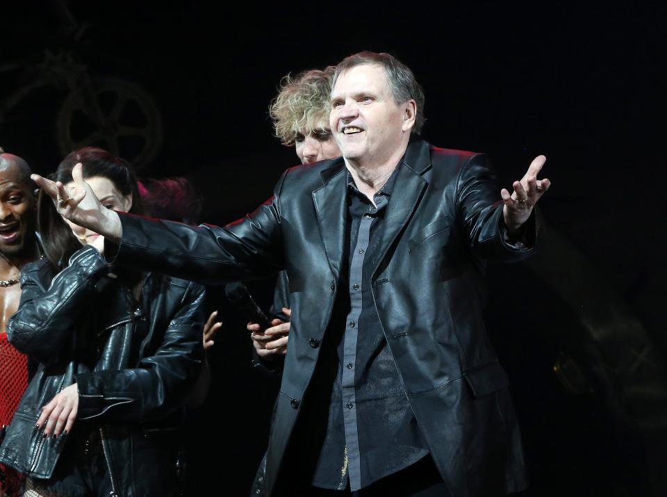 Meat Loaf stands on stage in a black jacket