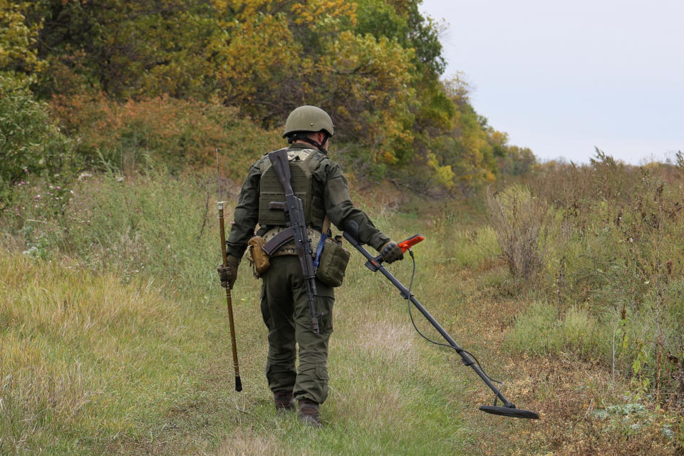 A member of the Ukrainian National Guard uses a metal detector to check an area near the Russian border in the Kharkiv region of Ukraine.