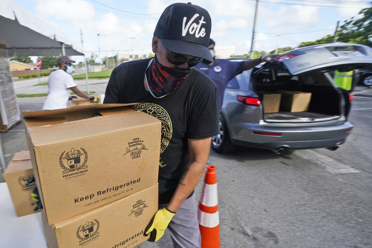 Volunteer Prince Rojo of North Miami, Fla., prepares to load boxes of food into a car at a food distribution event, Tuesday, Oct. 6, 2020, in Opa-locka, Fla. The drive-thru food distribution was hosted by Feeding South Florida. Shutdowns and restrictions have battered Florida's economy, leaving hundreds of thousands unemployed in the tourist-dependent state. (AP Photo/Wilfredo Lee)