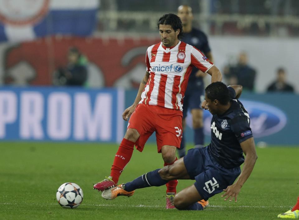 Olympiakos' Alejandro Dominguez, left, fights for the ball with Manchester United's Antonio Valencia during their Champions League, round of 16, first leg soccer match at Georgios Karaiskakis stadium, in Piraeus port, near Athens, on Tuesday, Feb. 25, 2014. (AP Photo/Thanassis Stavrakis)