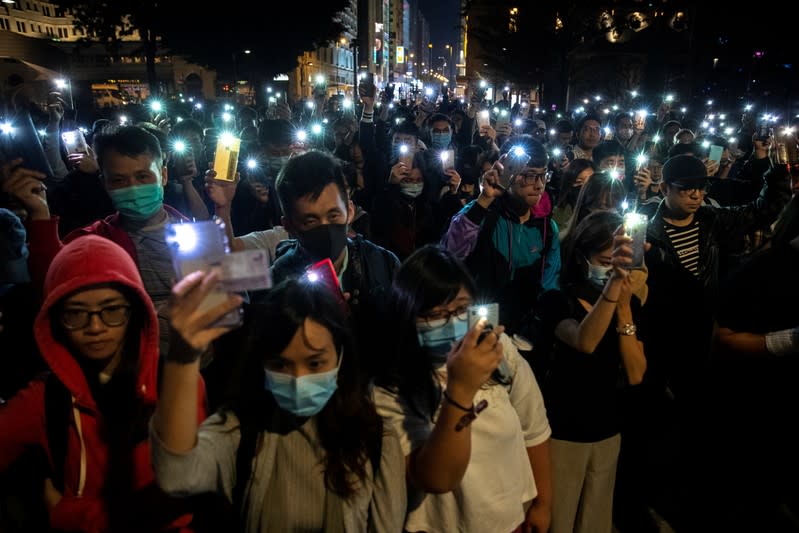 Protesters raise their mobile phones with lights on as they gather to show their support for protersters who are still inside the campus of the Hong Kong Polytechnic University (PolyU) in Hong Kong