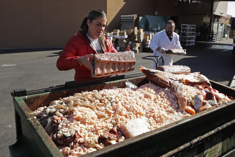 Meat department employees Jessica Powers and Brian Sullivan place spoiled meat in a dumpster behind Big John's Market in Healdsburg, Calif. as they help get the store ready to reopen Thursday, Oct. 31, 2019. Power was restored to the family-owned grocery store late Tuesday after being turned off for four days in an attempt to stem fires caused by wind-damaged power lines. Employees have been working since being allowed back into the town Wednesday to throw out spoiled stock and restock the store. (AP Photo/Charlie Riedel)