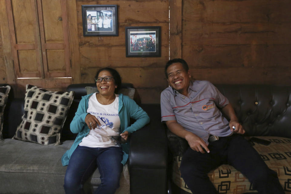 Ni Luh Erniati, left, laughs with Ali Fauzi during her visit to Fauzi's house in Tenggulun, East Java, Indonesia, on Saturday, April 27, 2019. Erniati, whose husband was killed in the 2002 Bali bombings, and Fauzi, a former bombmaker whose brothers helped orchestrate the Bali attack, have reconciled as part of a peacebuilding program bringing together ex-terrorists and victims. (AP Photo/Tatan Syuflana)