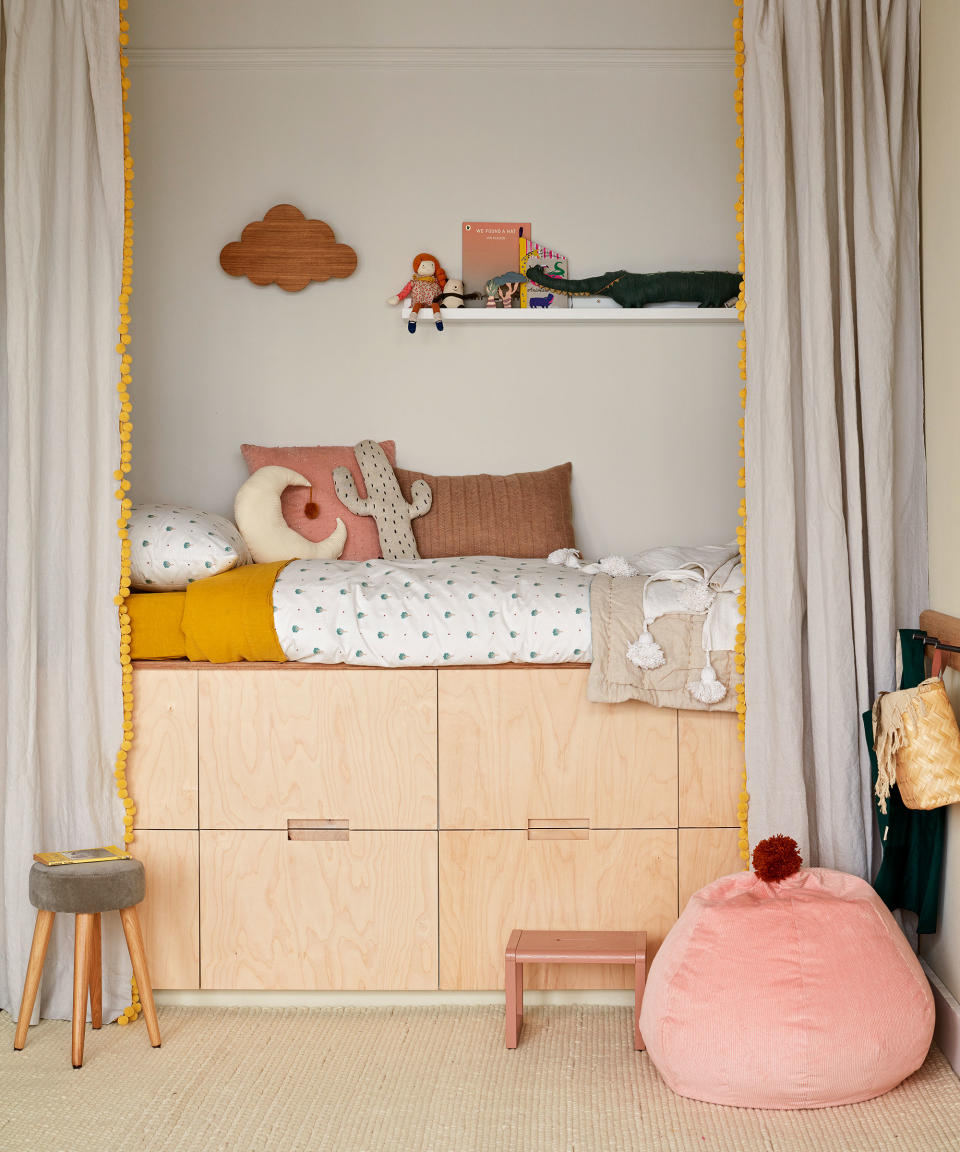 A built in bed in a kids room with curtains hanging on either side and cushion that looks like a boob