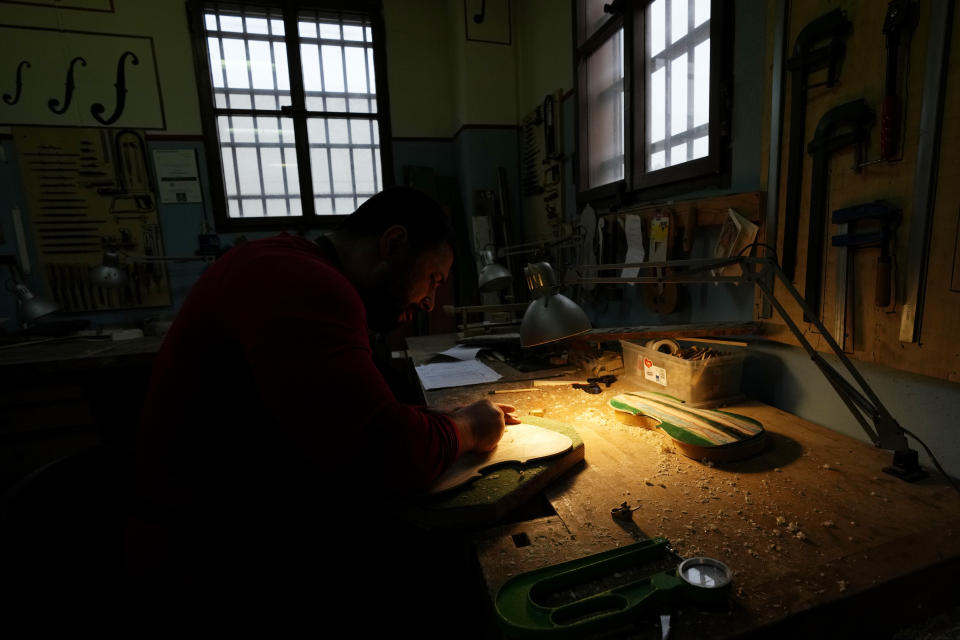 Milan's Opera maximum security prison inmate Nikolae (last name not available) works on the top plate of a violin made from the wood of wrecked migrants' boat in the prison's lab, near Milan, northern Italy, Friday, Feb. 9, 2024. Inmates at Opera used the wood of wrecked boats sailed by migrants across the Sicily Channel to craft the musical instruments that the 'Sea Orchestra' used during their debut at La Scala Opera House in Milan on Monday, Feb. 12, 2024. The violins, violas and cellos played by the Orchestra of the Sea in its debut performance Monday at Milan's famed Teatro all Scala carry with them tales of hardship. (AP Photo/Antonio Calanni)