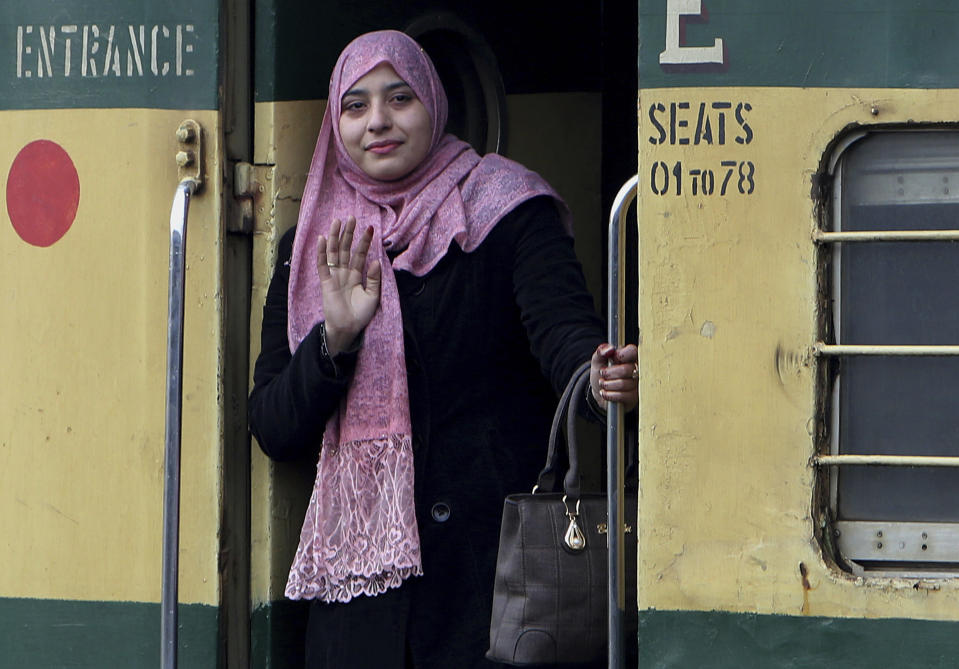 A passenger waves from the doorway of a train, on her way to India, after being stranded in Pakistan for a week, at Lahore Railway Station in Pakistan, Monday, March 4, 2019. A Pakistani railways official says a key train service between Pakistan and neighbouring India has been resumed, a sign on easing tensions between the two South Asian nuclear-armed rivals. (AP Photo/K.M. Chaudary)