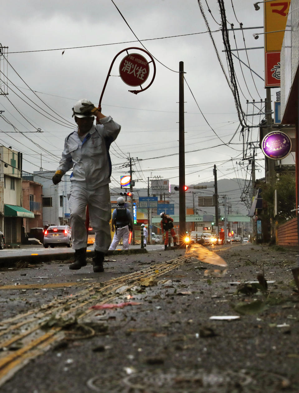 In this Sunday, Sept. 22, 2019, photo, police control the traffic after strong winds brought about by Typhoon Tapah swept Nobeoka, Miyazaki prefecture, southwestern Japan. The powerful typhoon lashed parts of Japan's southern islands with heavy rains and winds that caused flooding and some minor injuries. (Takuto Kaneko/Kyodo News via AP)