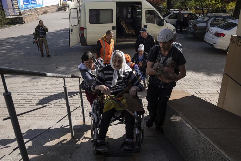 People help a disabled elderly woman onto an evacuation train in Pokrovsk, eastern Ukraine, Tuesday, April 26, 2022. (AP Photo/Evgeniy Maloletka)