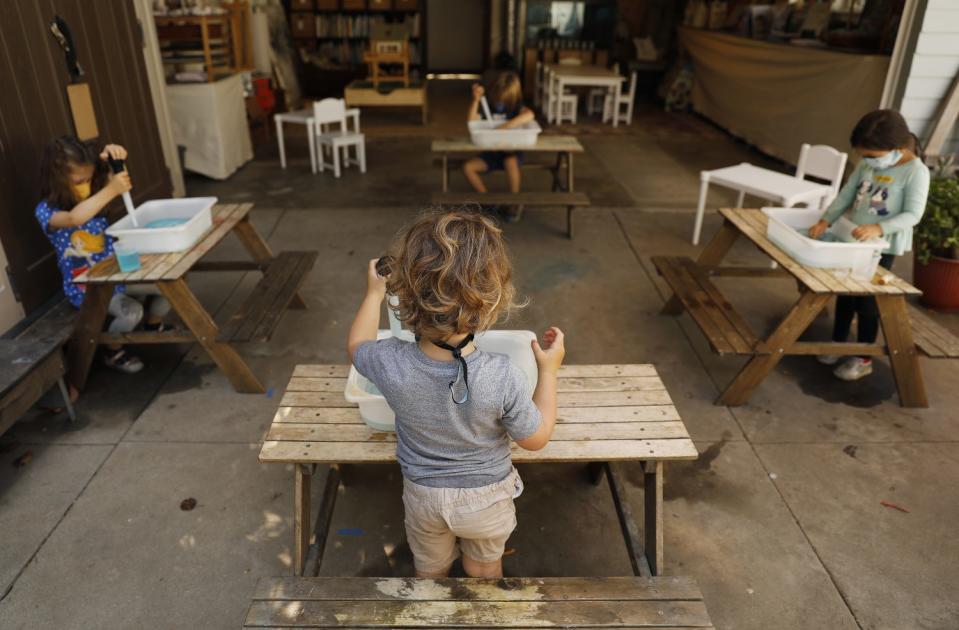 Children do activities at separate tables at Voyages Preschool.