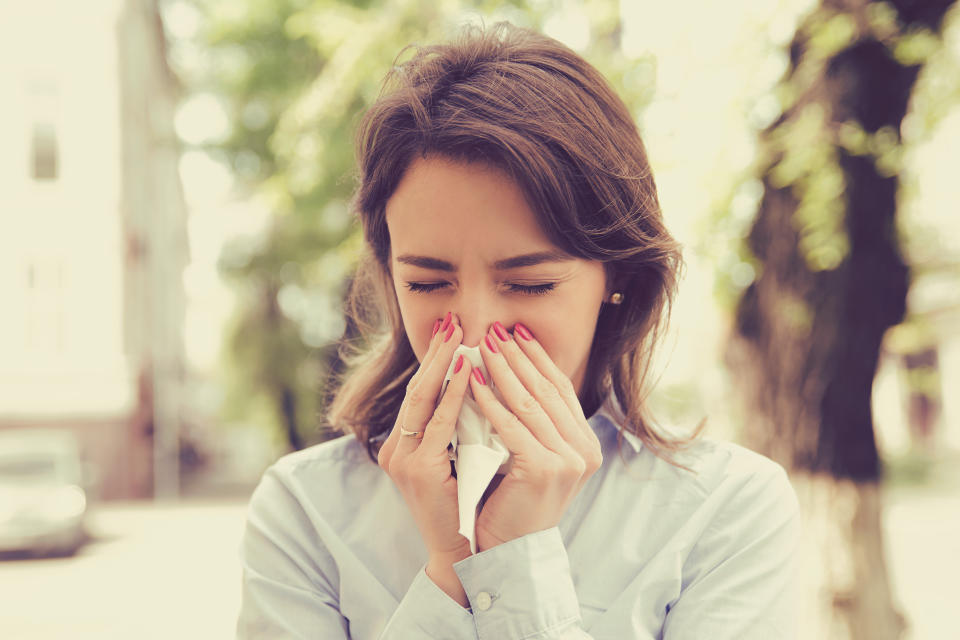 Woman with allergy symptoms blowing nose