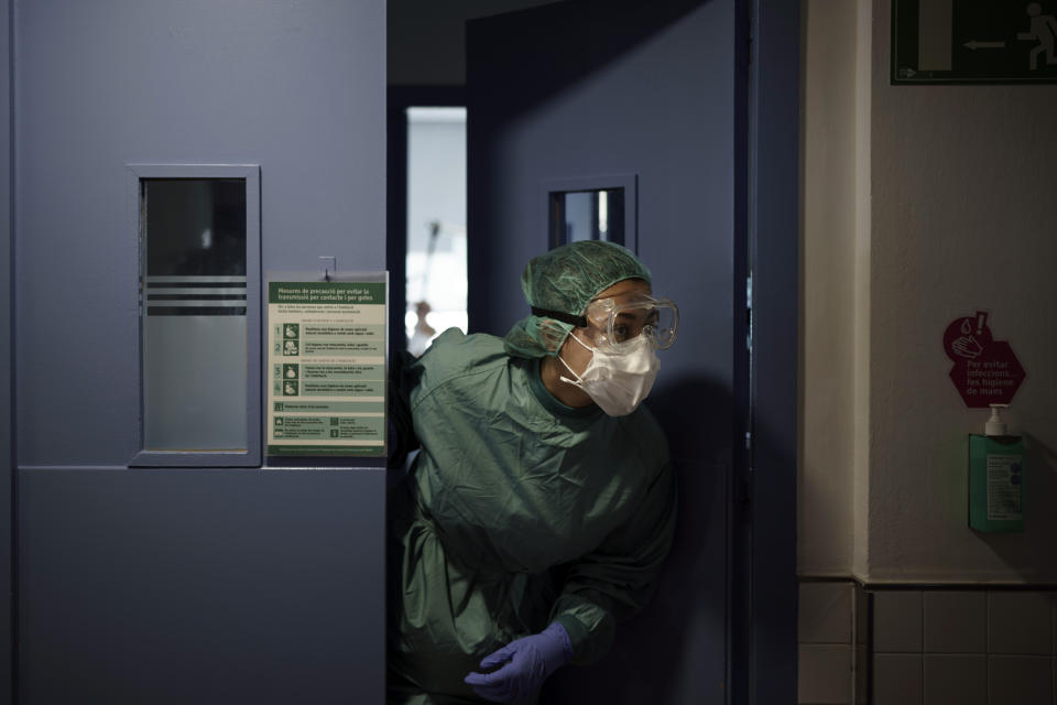 A health worker asks for additional supplies as she treats a COVID-19 patient in the Hospital del Mar in Barcelona, Spain, Friday, July 9, 2021. After a brief respite that brought its activity back to pre-pandemic routines, the hospital is once again rearranging staff shifts and moving patients around in its sprawling, seafront facilities to face a new surge of infections. (AP Photo/Felipe Dana)