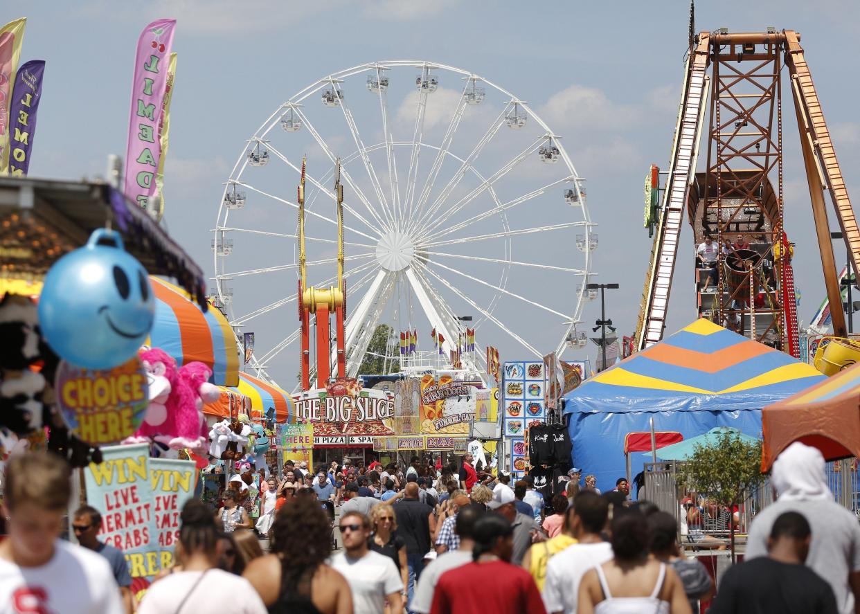 The 108-foot tall Ferris wheel from Talley Amusements towers over fairgoers in the Mountain Dew Midway at the Ohio State Fair in Columbus on Saturday, July 27, 2019. Thousands of visitors flocked to the fair with the 
warm, sunny weather on Saturday.