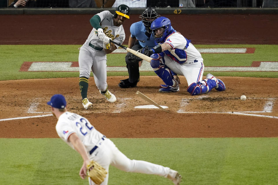 Oakland Athletics' Tony Kemp breaks his bat fouling off a pitch thrown by Texas Rangers starter Jon Gray (22) as catcher Jonah Heim and umpire John Tumpane look on in the third inning of a baseball game, Wednesday, July 13, 2022, in Arlington, Texas. Kemp grounded out in the at-bat. (AP Photo/Tony Gutierrez)