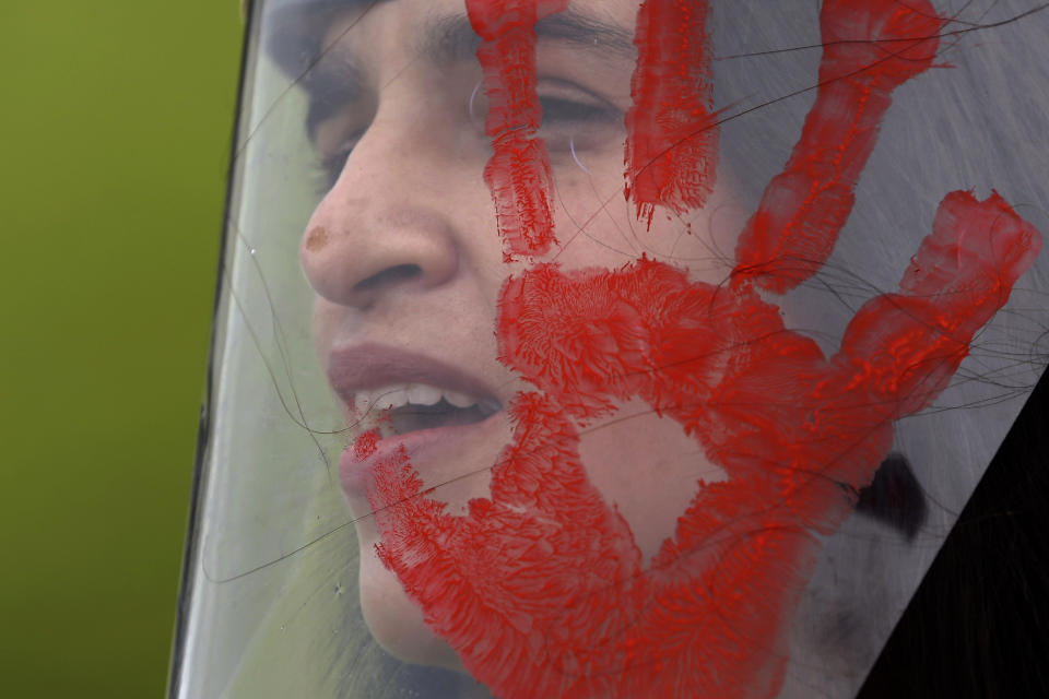 A demonstrator wears a face shield with a red handprint, mimicking blood, to protest Brazilian President Jair Bolsonaro's handling of the deadly coronavirus pandemic in Brasilia, Brazil, Wednesday, Dec. 23, 2020. Protesters also called for the immediate start of COVID-19 vaccinations. (AP Photo/Eraldo Peres)