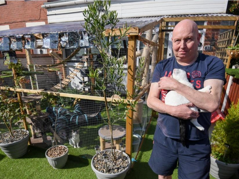 Adrian Marshall outside the catio. See SWNS story SWLEcat; A Blackpool couple who created a ‘Jungle Jim’s’ inspired adventure playground for their ten cats may be forced to tear down the vast structure after neighbours complained to the council. Lorraine and Adrian Marshall, of Pedders Lane, built the enormous ‘catio’ in their front garden in June after losing three of their precious pets to road accidents outside their home. But they were visited by a Blackpool Council planning enforcement officer earlier this month and told that, because they had not obtained planning permission for the structure, it would have to come down.