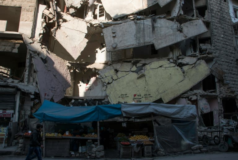 Syrians walk past a stall selling fruit and vegetables in the northern embattled Syrian city of Aleppo on February 9, 2016