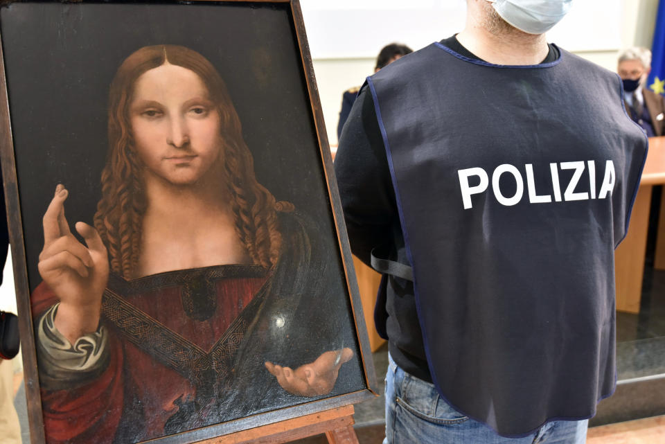 An Italian police officer stands by a copy of the “Salvator Mundi” (Savior of the World) by Leonardo da Vinci, in Naples, Italy, Wednesday, Jan. 20, 2021. Italian police have recovered a copy of Leonardo da Vinci’s 16th century “Salvator Mundi” painting of Jesus Christ that was stolen from a Naples church without the priests even realizing it was gone. The discovery was made over the weekend when Naples police working on a bigger operation found the painting hidden in an apartment. Police chief Alfredo Fabbrocini said the owner offered a “less than credible” explanation that he had “casually” bought it at a small market. (Italian Police via AP)