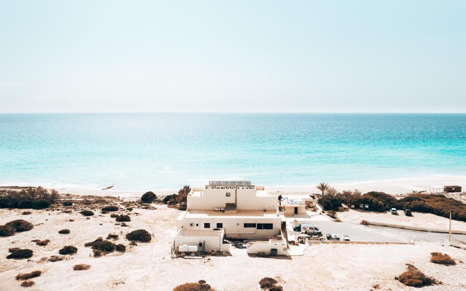 white boxy building on beach looking out over blue sea