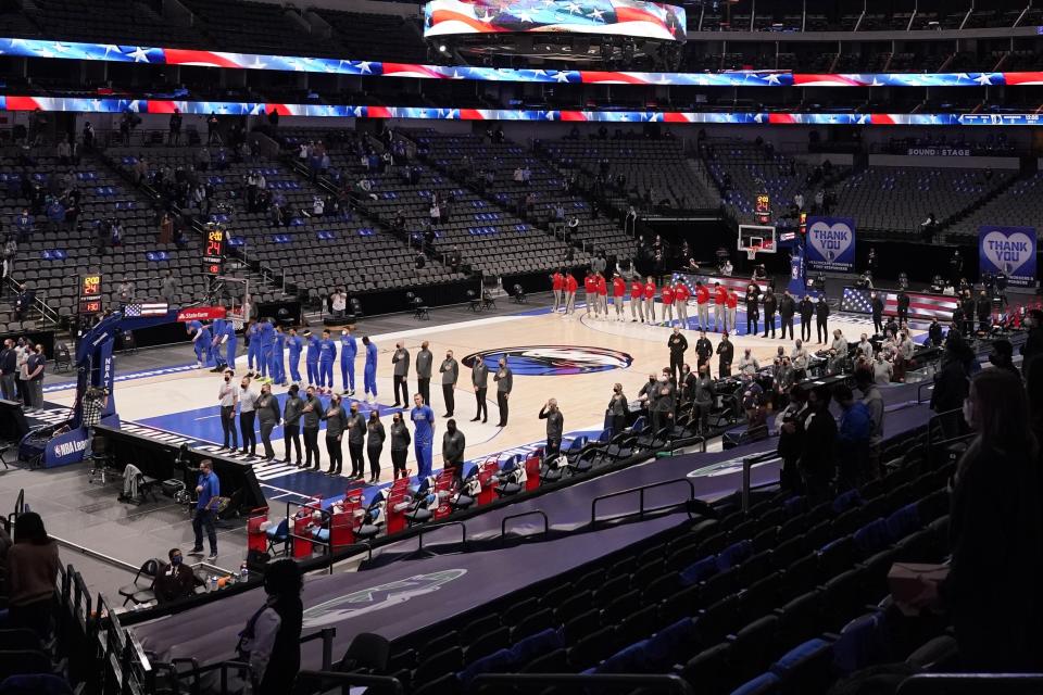 The Dallas Mavericks and Atlanta Hawks, along with a limited fan attendance stand during the playing of the national anthem before the first half of an NBA basketball game in Dallas, Wednesday, Feb. 10, 2021. (AP Photo/Tony Gutierrez)