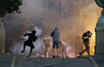 Protesters clash with Serbian riot police in Belgrade, Serbia, Wednesday, July 8, 2020. Police have fired tear gas at protesters in Serbia's capital during the second day of demonstrations against the president's handling of the country's coronavirus outbreak. President Aleksandar Vucic backtracked on his plans to reinstate a coronavirus lockdown in Belgrade this week, but it didn't stop people from firing flares and throwing stones while trying to storm the downtown parliament building. (AP Photo/Darko Vojinovic)