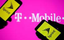 A smartphones with Sprint logo are seen in front of a screen projection of T-mobile logo, in this picture illustration