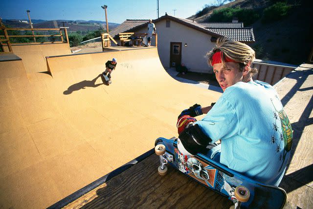 <p>Paul Harris/Getty </p> Tony Hawk sitting on a skateboarding ramp at age 18 in 1986