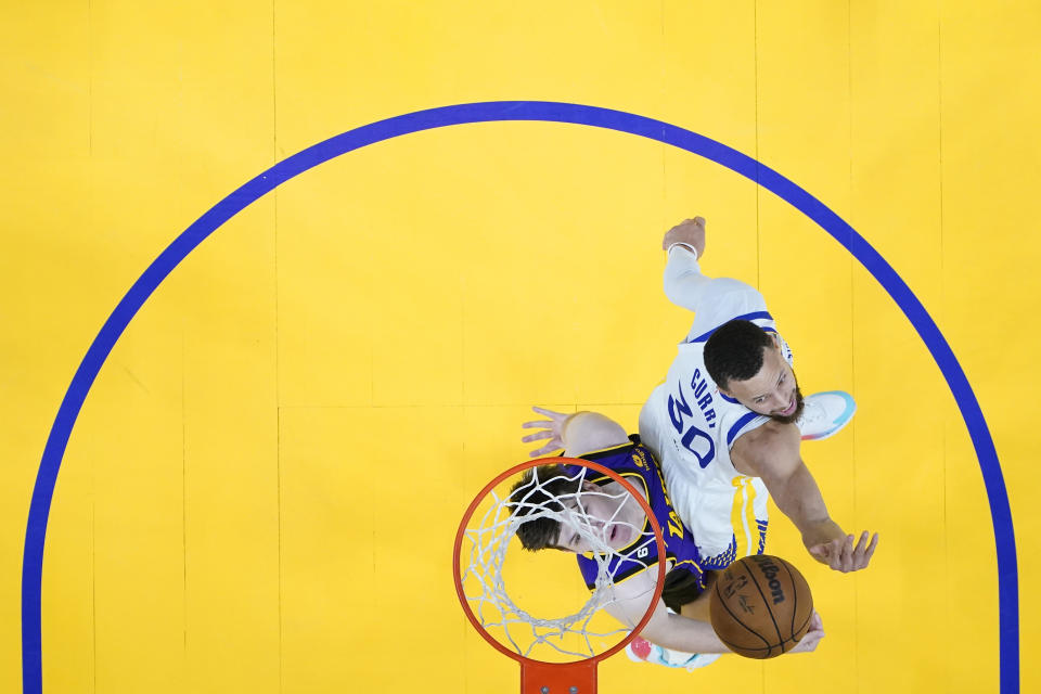 Los Angeles Lakers guard Austin Reaves, left, shoots while defended by Golden State Warriors guard Stephen Curry (30) during the second half of Game 2 of an NBA basketball Western Conference semifinal game, Thursday, May 4, 2023, in San Francisco. (AP Photo/Godofredo A. Vásquez)