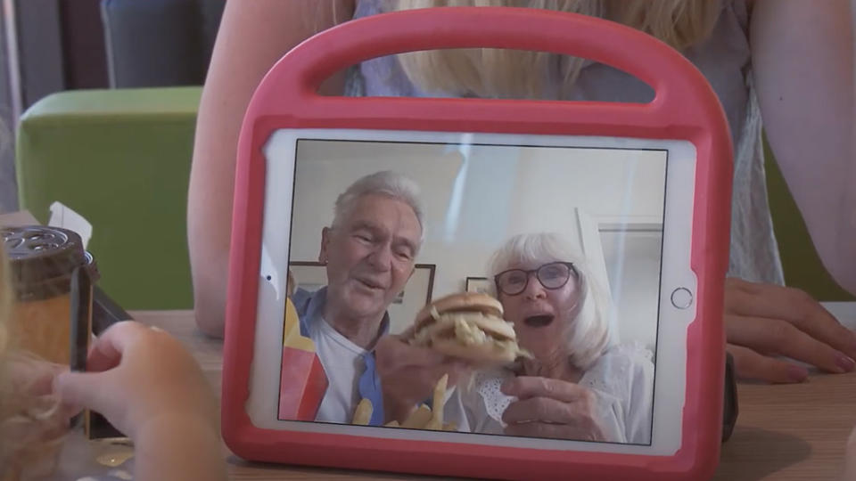 Grandparents sharing a happy meal with their grandchildren over a video chat.