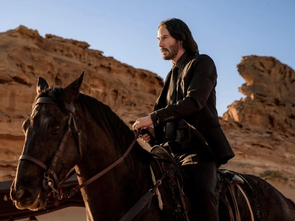 Keanu Reeves as John Wick riding a horse.