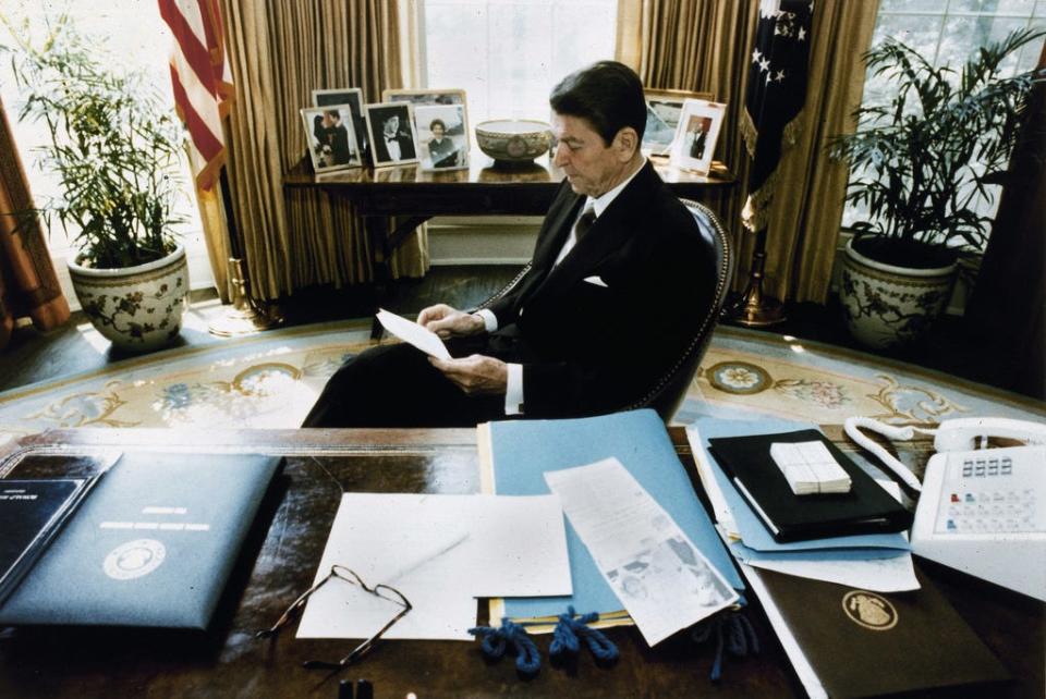 In this photo released by the White House, President Ronald Reagan goes over his recent speech to Congress on the economy during a rare quiet moment in the White House Oval Office, 1981.