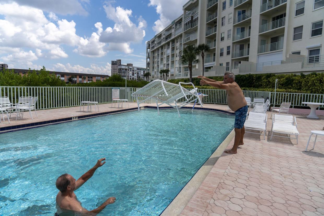 Resident and maintenance technician Scott Keeler tosses a pool chaise in the pool to store underwater to George Shukis, president of the Sunrise Owner's Association at Harbourside Condominiums, in preparation for the arrival of Hurricane Ian, Monday, Sept. 26, 2022, in South Pasadena, Fla. Ian was growing stronger as it approached the western tip of Cuba on a track to hit the west coast of Florida as a major hurricane as early as Wednesday.