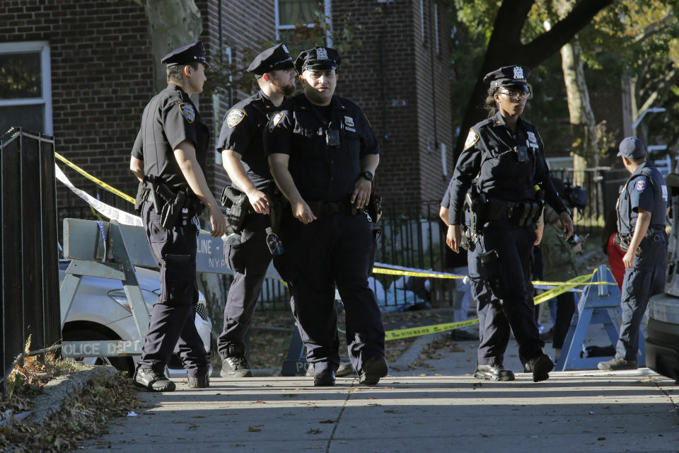 Emergency personnel walk near the scene of a fatal shooting of a New York City police officer in the Bronx borough of New York, Sunday, Sept. 29, 2019. (AP Photo/Seth Wenig)