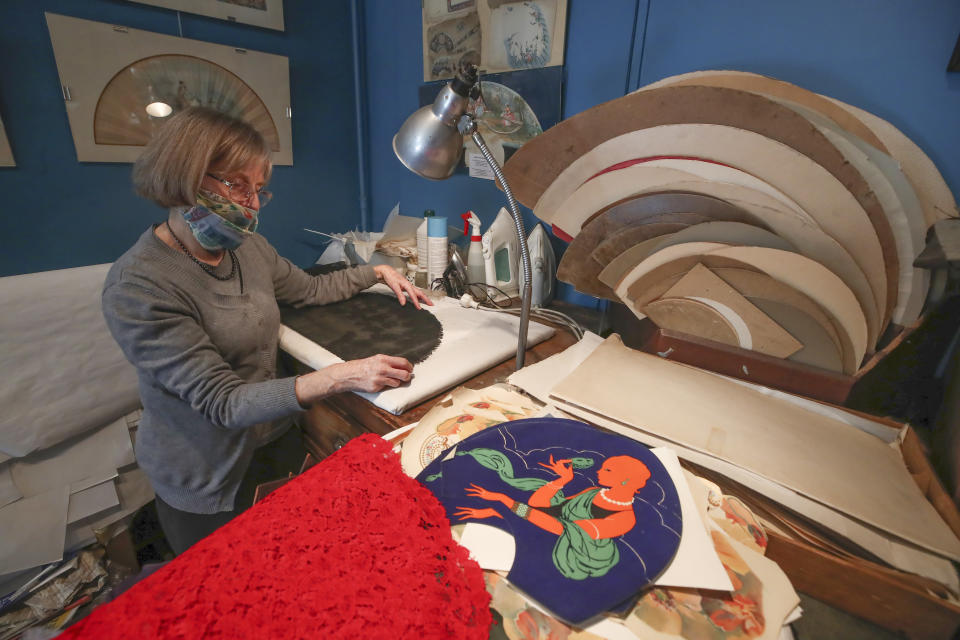 Anne Hoguet, 74, fan-maker and director of the hand fan-making museum works in her workshop in Paris, Wednesday, Jan. 20, 2021. Just like the leaves of its gilded fans, France's storied hand fan-making museum could fold up and vanish. The splendid Musee de l'Eventail in Paris, a classed historical monument, is the culture world's latest coronavirus victim. (AP Photo/Michel Euler)