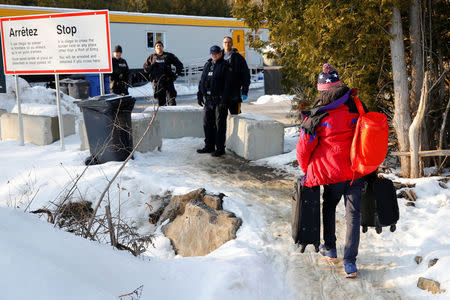 Royal Canadian Mounted Police (RCMP) officers look on as a man crosses the US-Canada border into Canada from Champlain, New York, U.S., February 14, 2018. Picture taken February 14, 2018. REUTERS/Chris Wattie