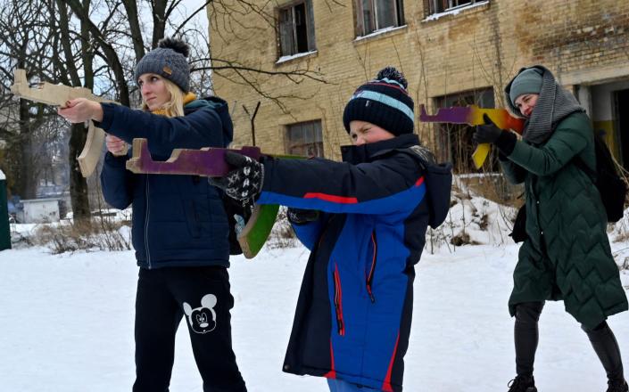 Civilians hold wooden replicas of Kalashnikov rifles as they take part in a training session at an abandoned factory in the Ukrainian capital, Kyiv, on Sunday - Sergei Supinsky/AFP via Getty Images