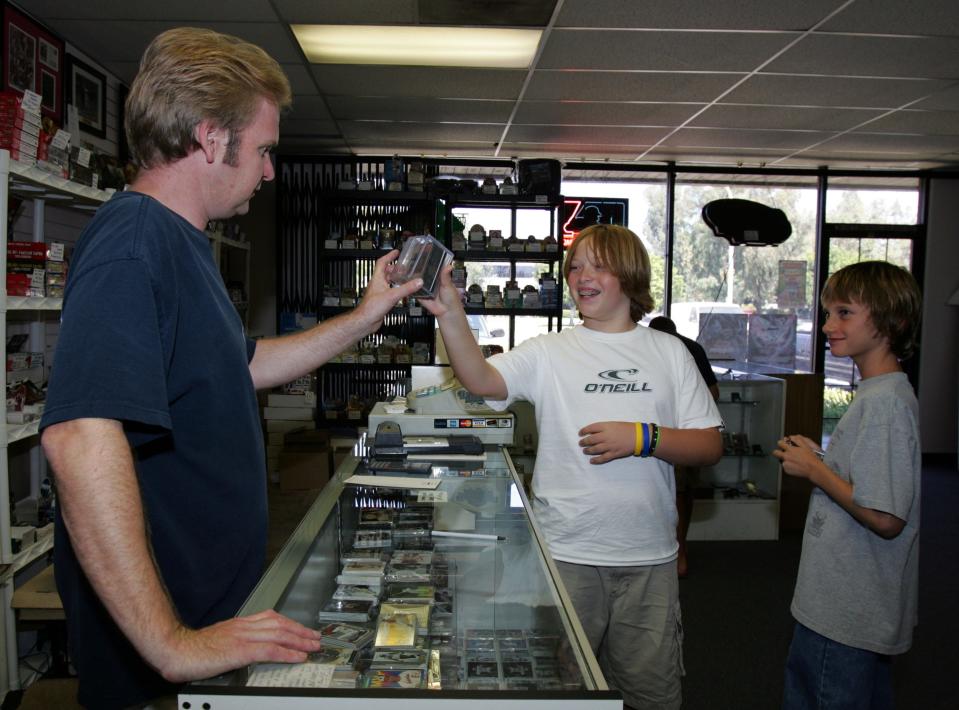 In this 2005 photo, Mike Mittrick attends to customers Max Sutton, center, and Sam Killan, in his 52 Mantle Card store in Brea, California.