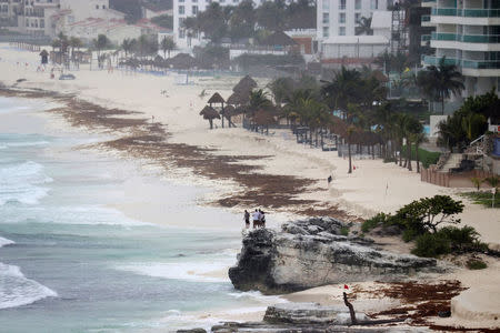 Tourists stand on a rock as subtropical storm Alberto approaches Cancun, Mexico May 25, 2018. REUTERS/Israel Leal