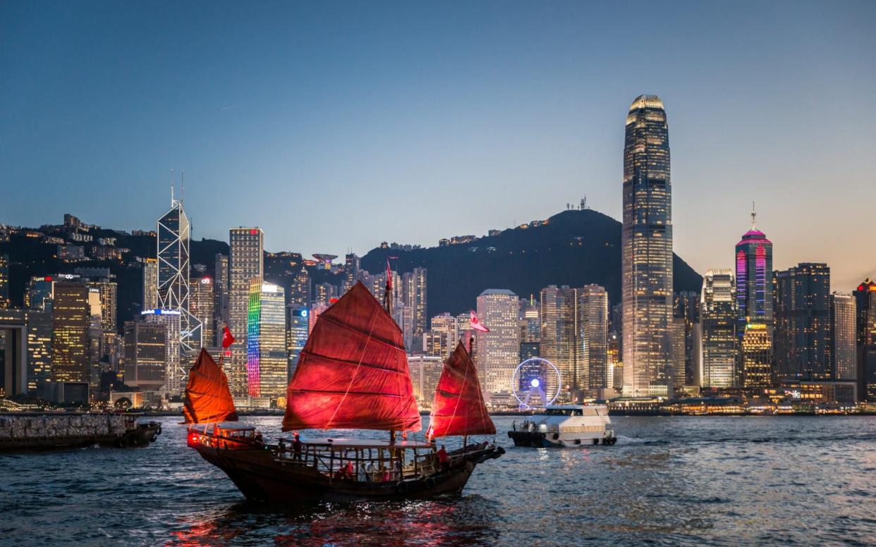 Traditional junk boat sailing across Victoria Harbour, Hong Kong. Traditional Junk Boat at Dusk - Getty