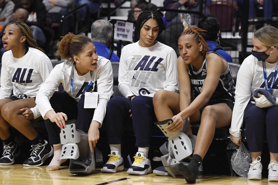 Georgetown's Kelsey Ransom second from left, and Georgetown's Jillian Archer second from right, trade boots for their injuries while Georgetown's Jazmyn Harmon, center, looks on in the second half of an NCAA college basketball game against Connecticut in the Big East tournament quarterfinals at Mohegan Sun Arena, Saturday, March 5, 2022, in Uncasville, Conn. (AP Photo/Jessica Hill)