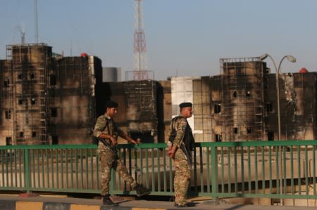 Members of Iraqi police stand guard in front of Maysan Governorate building, which was burnt by demonstrators during a protest over unemployment, corruption and poor public services, in Maysan province, south of Bagdad