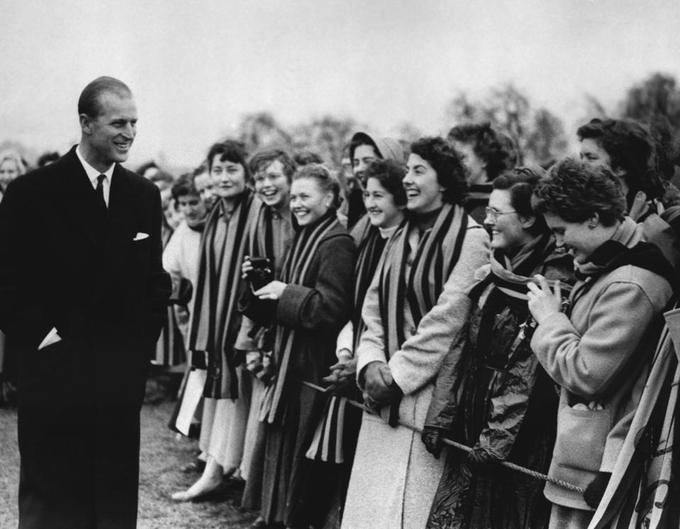 En esta foto del 10 de marzo de 1957, el príncipe Felipe de Gran Bretaña es saludado por estudiantes del St. Mary's College en Cheltenham, Inglaterra, al salir del campo de juego del St. Paul's College. (AP Foto/Archivo)