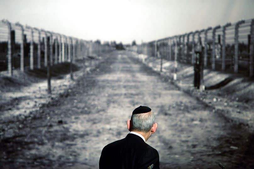 Rabbi Israel Singer, Chairman of the World Jewish Congress, looks at a photo showing a corridor in the Auschwitz concentration camp.